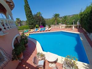 a swimming pool on a patio with chairs and a building at Casa Cachito in Benissa