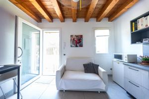 a living room with a white chair and a kitchen at B&B We CaRe Appartamento in Lendinara