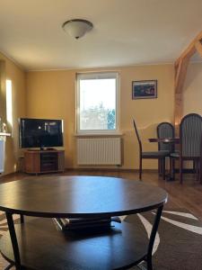 a living room with a table and a tv at Sodyba Miegėnuose in Miegėnai
