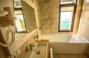 a bathroom with a tub and a sink and a window at Hotel Montana in Sarpi