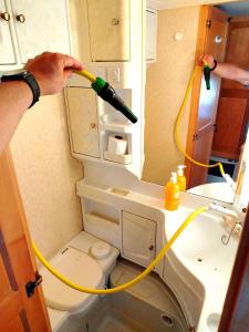a person is washing a toilet with a hose at Przyczepa kempingowa nad jez Gardno in Gardna Wielka +17 photos