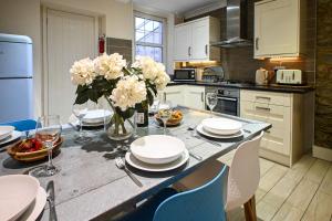 a kitchen with a table with plates and flowers on it at Stade Cottage in Hythe