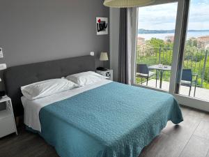 a bedroom with a bed with a blue blanket and a balcony at Stella Maggiore in Verbania