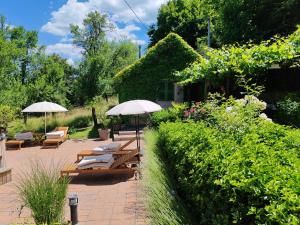 a patio with lounge chairs and umbrellas in a garden at Holiday Home Modric in Otočac