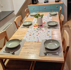 a wooden table with plates and utensils on it at HyggeHome Strandelhjørn in Vojens +12 photos