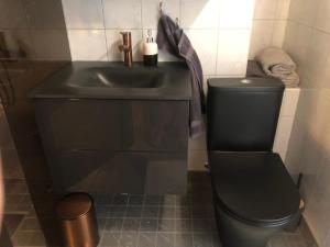 a bathroom with a black toilet and a sink at Aavik Apartment in Kuressaare +11 photos