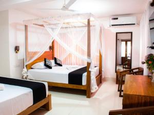 a hotel room with two beds and a table at Villa Hima Arana in Galle