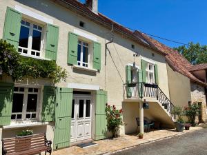 a building with green shutters and a bench in front at Le Charme du Perigord - chambre & table d'hotes in Saint-Sulpice-dʼExcideuil
