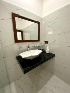 a white bathroom with a sink and a mirror at Ameliora Ella in Ella