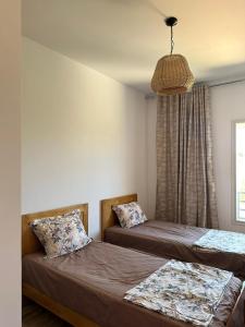 a bedroom with two beds and a pendant light at Diar Jabal Villa S2 in Banī ‘Aţāʼ +40 photos