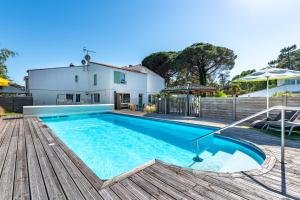 a swimming pool in front of a house at Hôtel Le Parasol in Ars-en-Ré