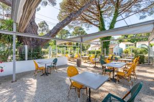 an outdoor seating area with tables and chairs at Hôtel Le Parasol in Ars-en-Ré
