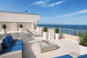 a patio with blue furniture and the ocean in the background at Hotel Orizzonte in Letojanni