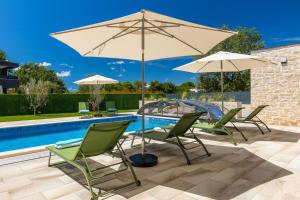 a patio with chairs and an umbrella and a pool at Villa Dell Arte in Žminj