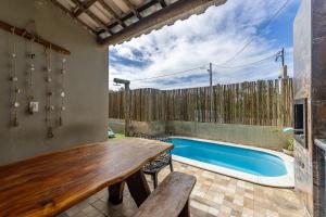 a patio with a wooden table and a swimming pool at Casa inteligente com 4 suítes e piscina - 160D in Japaratinga