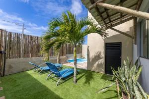 two blue chairs and a palm tree in a yard at Casa inteligente com 4 suítes e piscina - 160D in Japaratinga