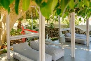 a pavilion with white pillows and tables and trees at Smaragdi in Perivolos