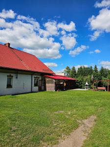 a building with a red roof and a grass field at Jaśmin in Budry