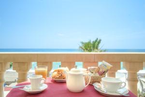 a table with cups and plates of food on a balcony at Hotel Orizzonte in Letojanni