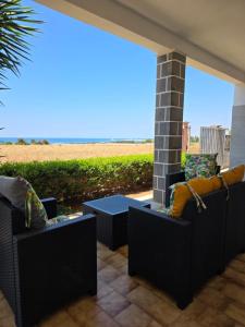 a patio with two chairs and a table and a view of the beach at Villetta Lu Sule in Porto Cesareo