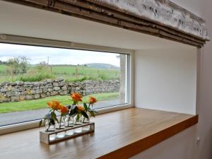 a window in a room with orange flowers in vases at Longcroft Dairy in Oyne +4 photos