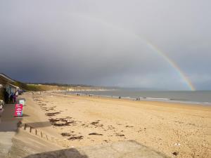 a rainbow over a beach with a group of people at Sycamore Lodge in Sewerby
