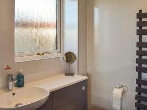 a bathroom with a sink and a mirror and a window at Lowesmuir Cottage in Cumnock