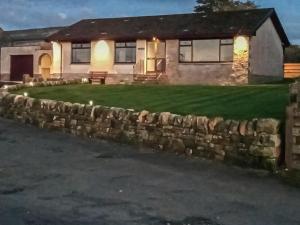 a stone retaining wall in front of a house at Lowesmuir Cottage in Cumnock