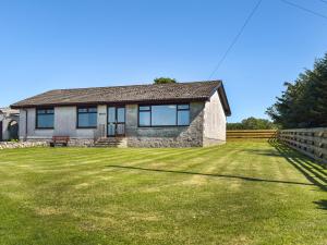 a house with a grassy yard in front of it at Lowesmuir Cottage in Cumnock