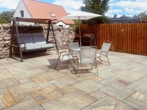 a patio with chairs and a swing and an umbrella at Royal Border Retreat in Berwick-Upon-Tweed