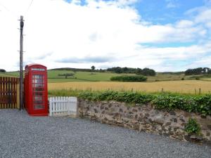 a red phone booth sitting next to a stone wall at Longcroft Cottage - 28233 in Oyne +7 photos
