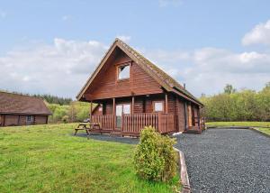a small wooden cabin with a bench in a field at Benview Holiday Lodges in Gartmore