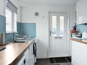 a kitchen with a sink and a white door at Boatmans Cottage - 27787 in Portessie