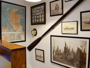 a wall with framed pictures and a stair case at Boatmans Cottage - 27787 in Portessie