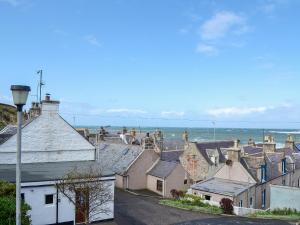 a group of houses with the ocean in the background at Boatmans Cottage - 27787 in Portessie