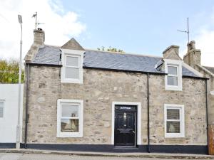 a stone house with a black door and white windows at Boatmans Cottage - 27787 in Portessie +17 photos