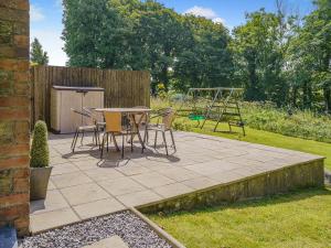 a patio with a table and chairs and a playground at Y Beudy - Uk49917 in Penclawdd