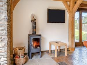 a wood stove in a room with a tv at Y Beudy - Uk49917 in Penclawdd