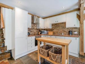 a kitchen with white cabinets and a wooden table at Y Beudy - Uk49917 in Penclawdd +17 photos