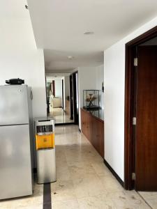 a kitchen with a refrigerator and a living room at Apartment 3BR Prima Bragacitywalk in Bandung