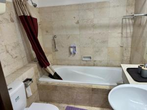 a bathroom with a tub and a toilet and a sink at Apartment 3BR Prima Bragacitywalk in Bandung