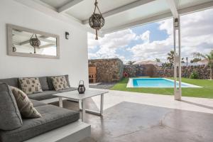 a living room with a couch and a table and a pool at Villa La Era 1 in El Cotillo