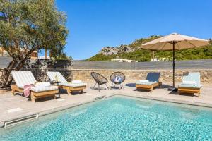 a swimming pool with lounge chairs and an umbrella at La Casa Di Pietre 1 in Kiotari