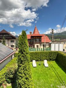 a house with two white chairs in a yard at Casa in inima Bucovinei in Câmpulung Moldovenesc