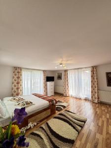 a bedroom with a bed in a room with windows at Casa in inima Bucovinei in Câmpulung Moldovenesc