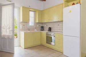 a kitchen with yellow cabinets and a white refrigerator at Studios Poulati in Artemonas