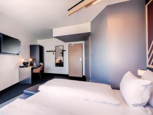 a bedroom with a white bed and a desk at B&B HOTEL Fürth-Hardhöhe in Fürth +16 photos