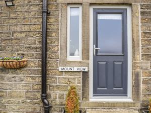 a brick house with a blue door and a mount view sign at Mount View - Uk48425 in Holmfirth