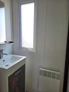a white bathroom with a sink and a window at Camping Val de Boutonne in Saint-Jean-dʼAngély +60 photos