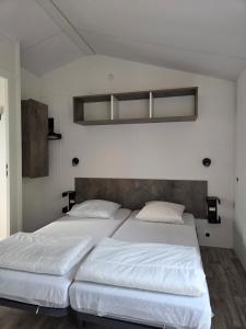 two beds in a bedroom with white walls at Camping Val de Boutonne in Saint-Jean-dʼAngély